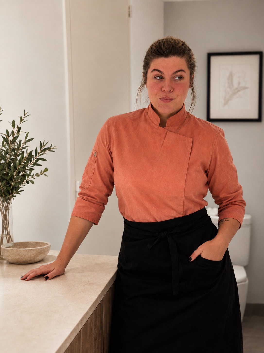 Alexia con chaqueta coral, apoyada en la mesada de su cocina